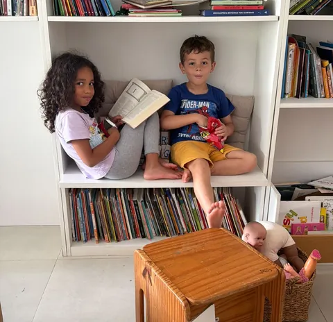 Dois dos filhos lendo sentados na estante de livros