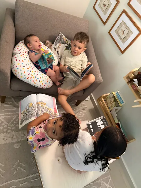 Os filhos lendo juntos no sofá, com a bebê no colo da almofada